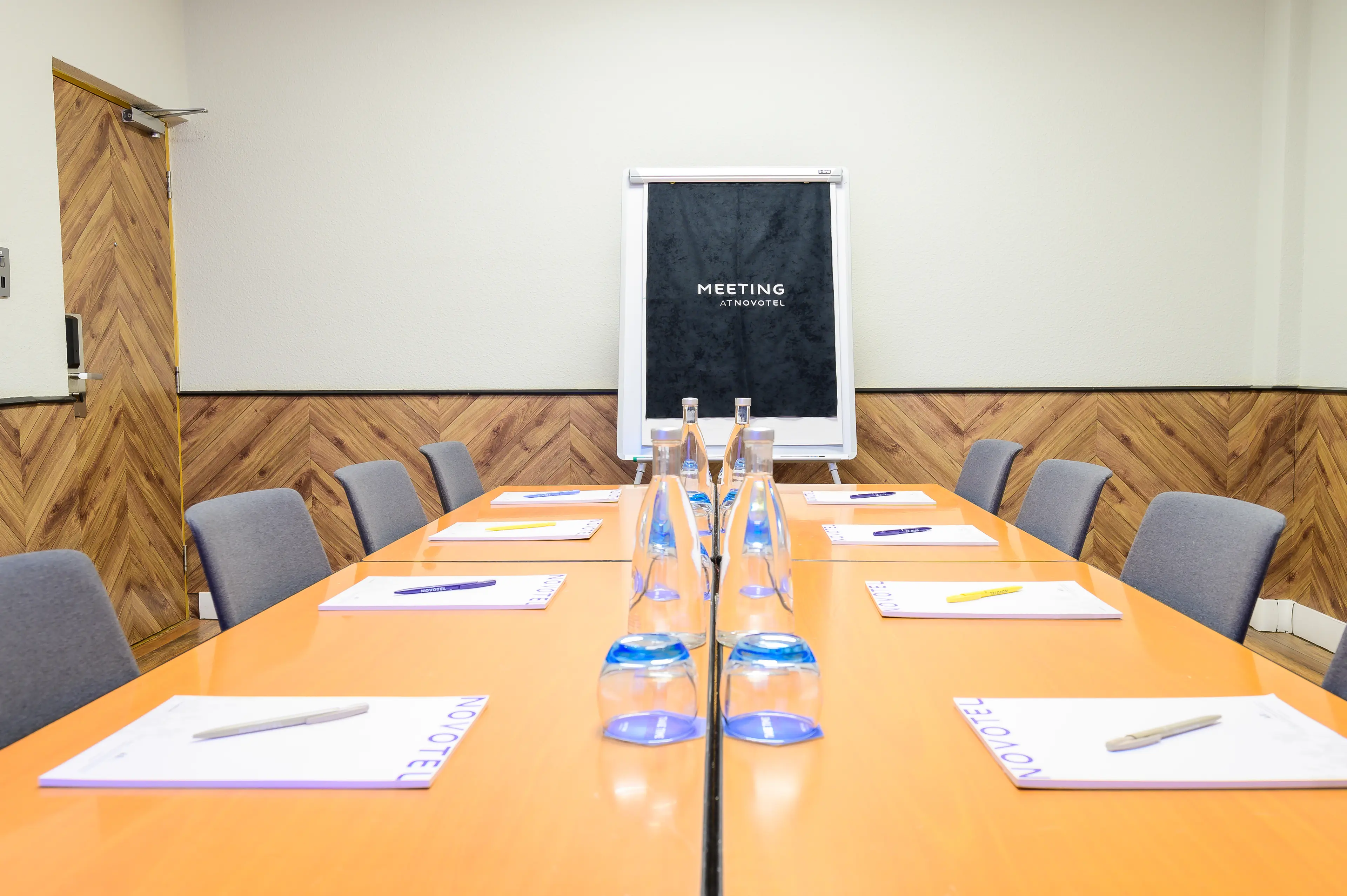 Meeting room at Novotel Birmingham with long table, notepads for corporate events.