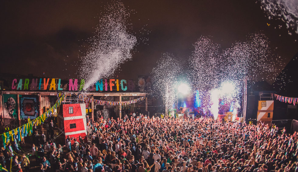 Vibrant outdoor festival at The Rainbow Venues with colorful decorations and lively crowd.