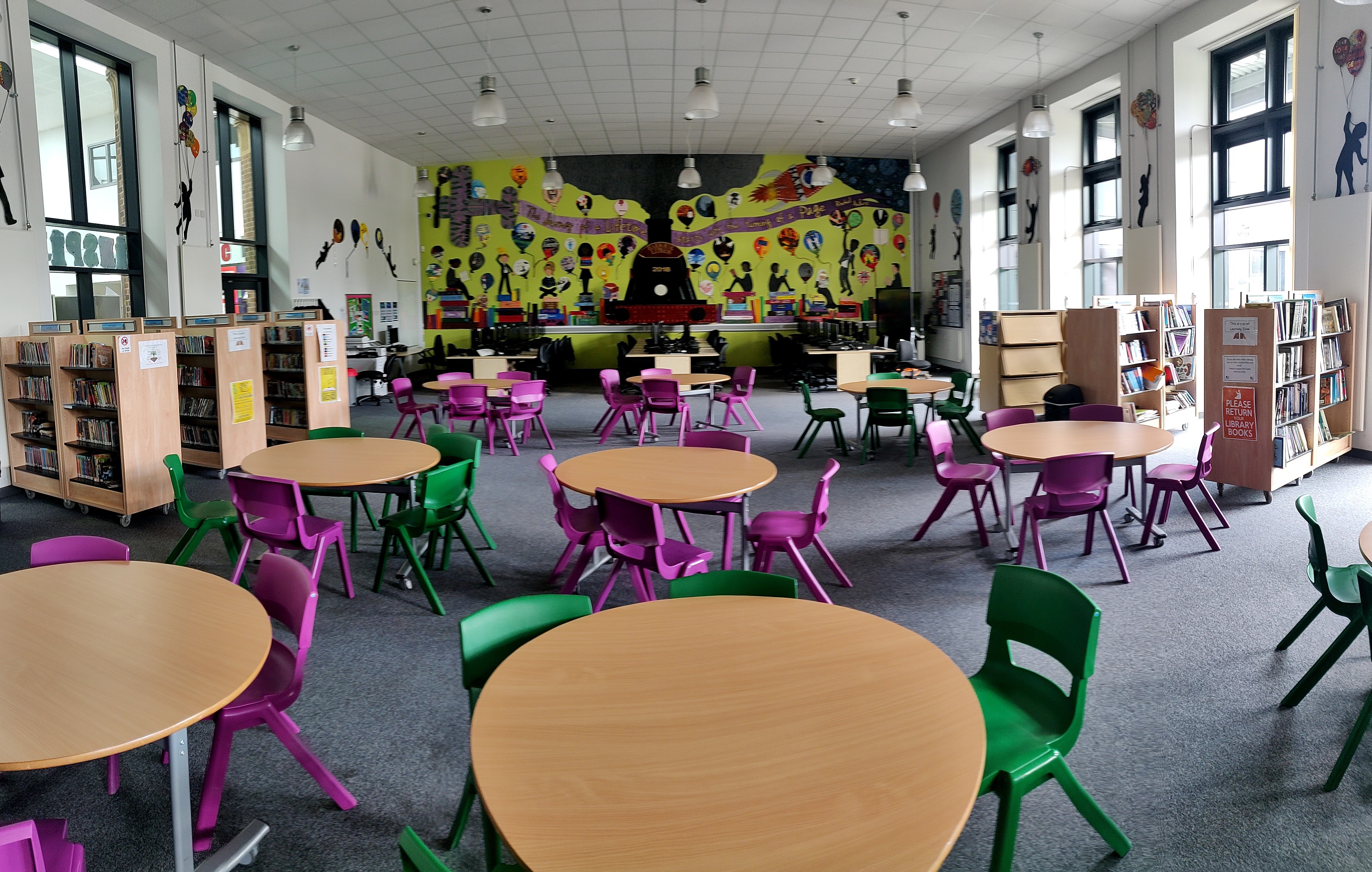 Vibrant Harborne Academy Main Hall with flexible seating for community events and workshops.