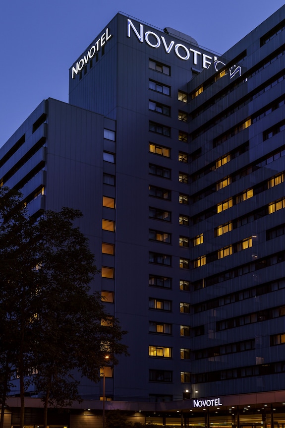 Modern hotel building at dusk, warm lights glowing, ideal for conferences and events.