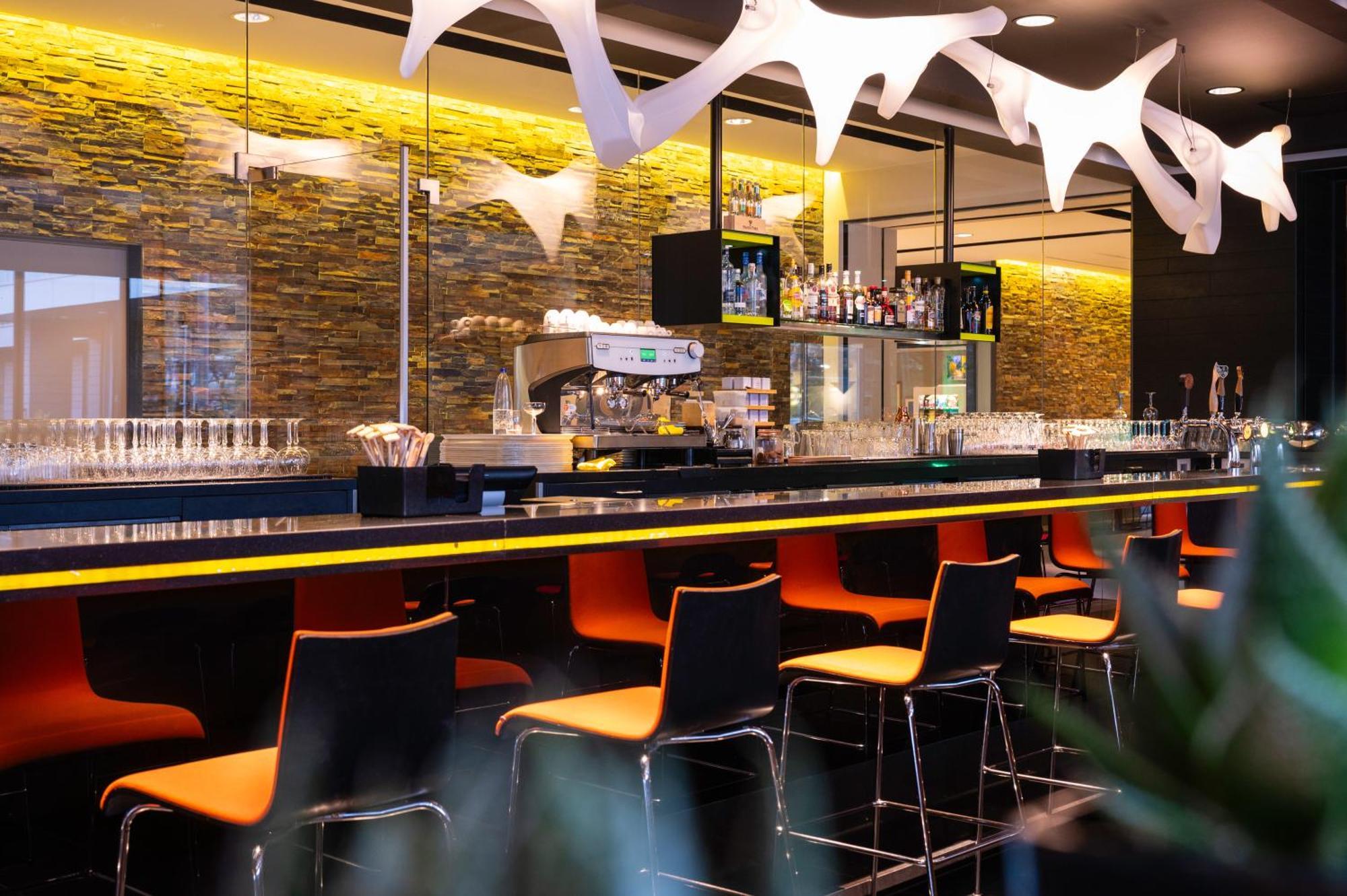 Modern bar at Novotel Amsterdam City with vibrant seating, perfect for events.