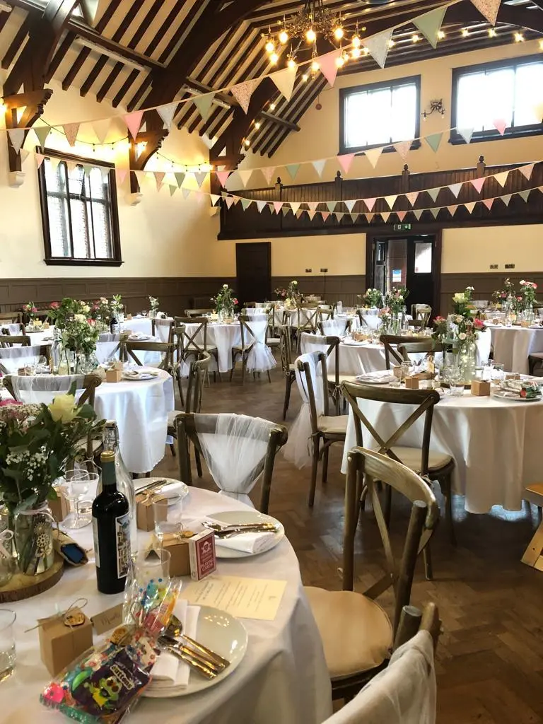 Elegant Main Hall at Waddesdon, adorned for a wedding with floral centerpieces and bunting.