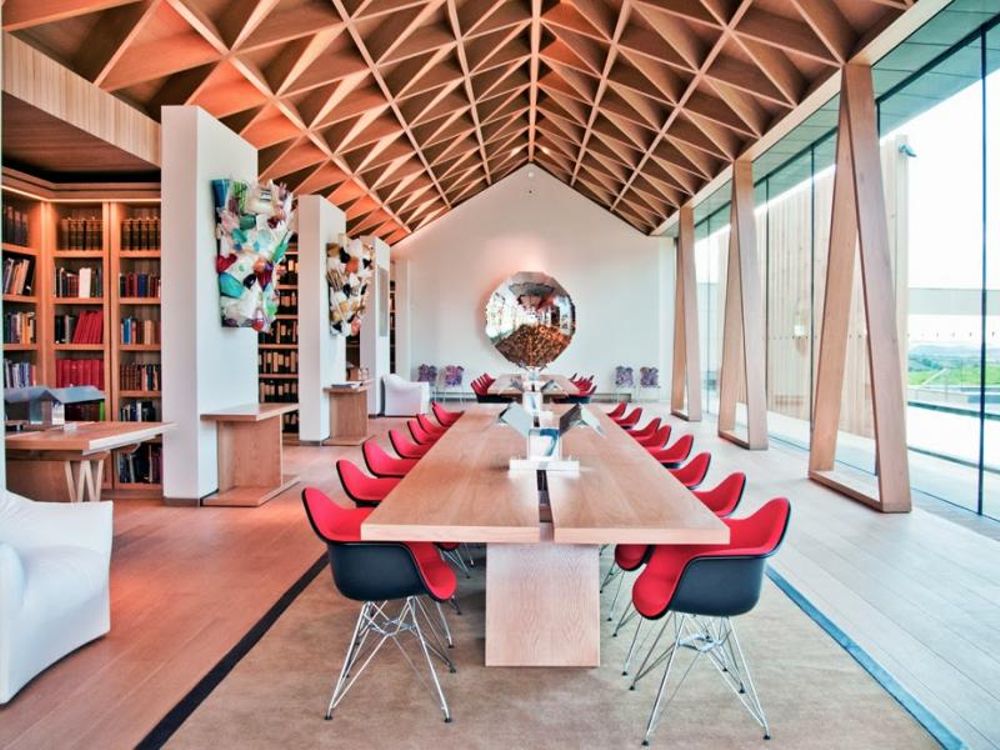 Modern meeting room with wooden table and red chairs, perfect for creative brainstorming.