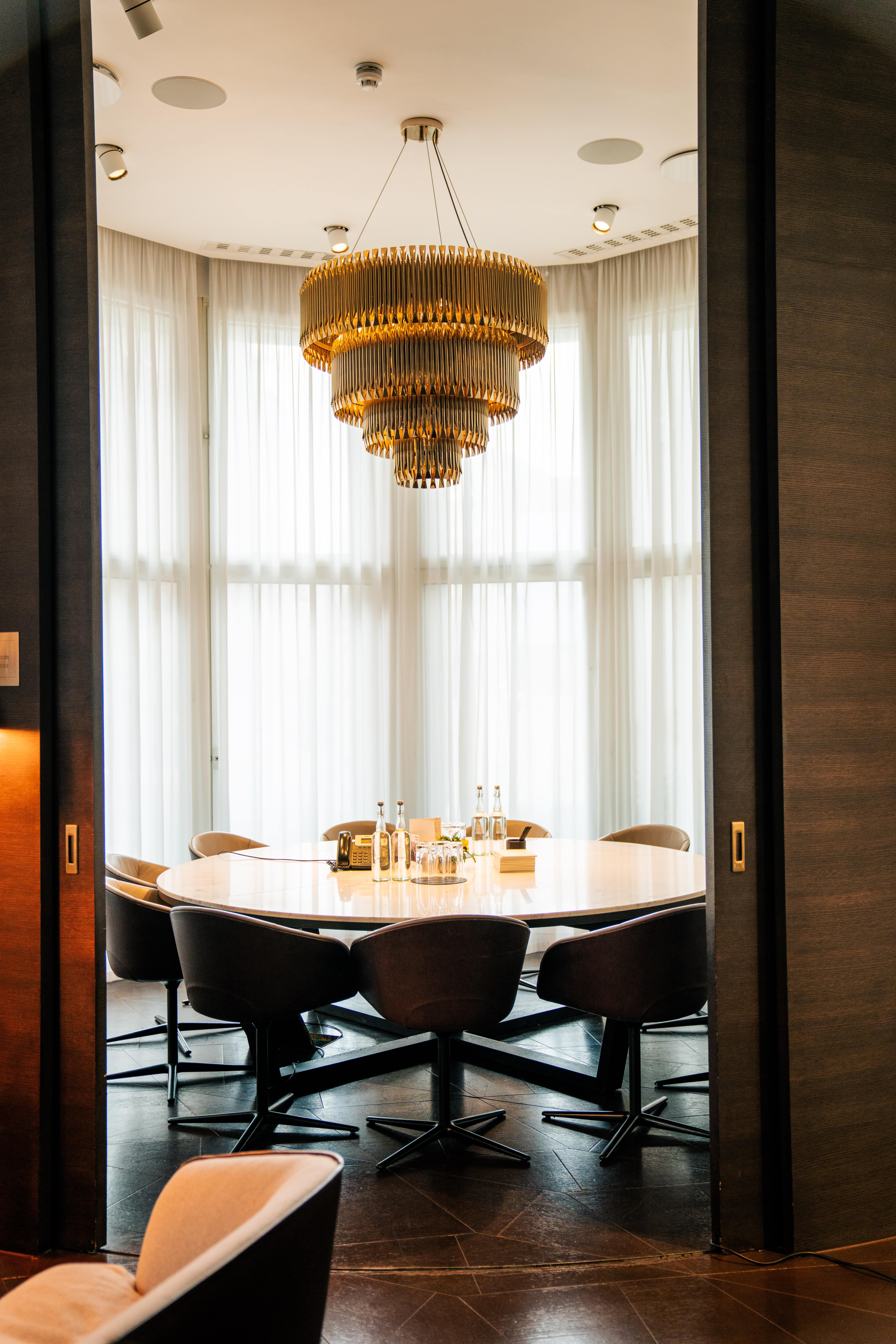 Sophisticated meeting space at The Ground Round with round table and elegant chandelier.