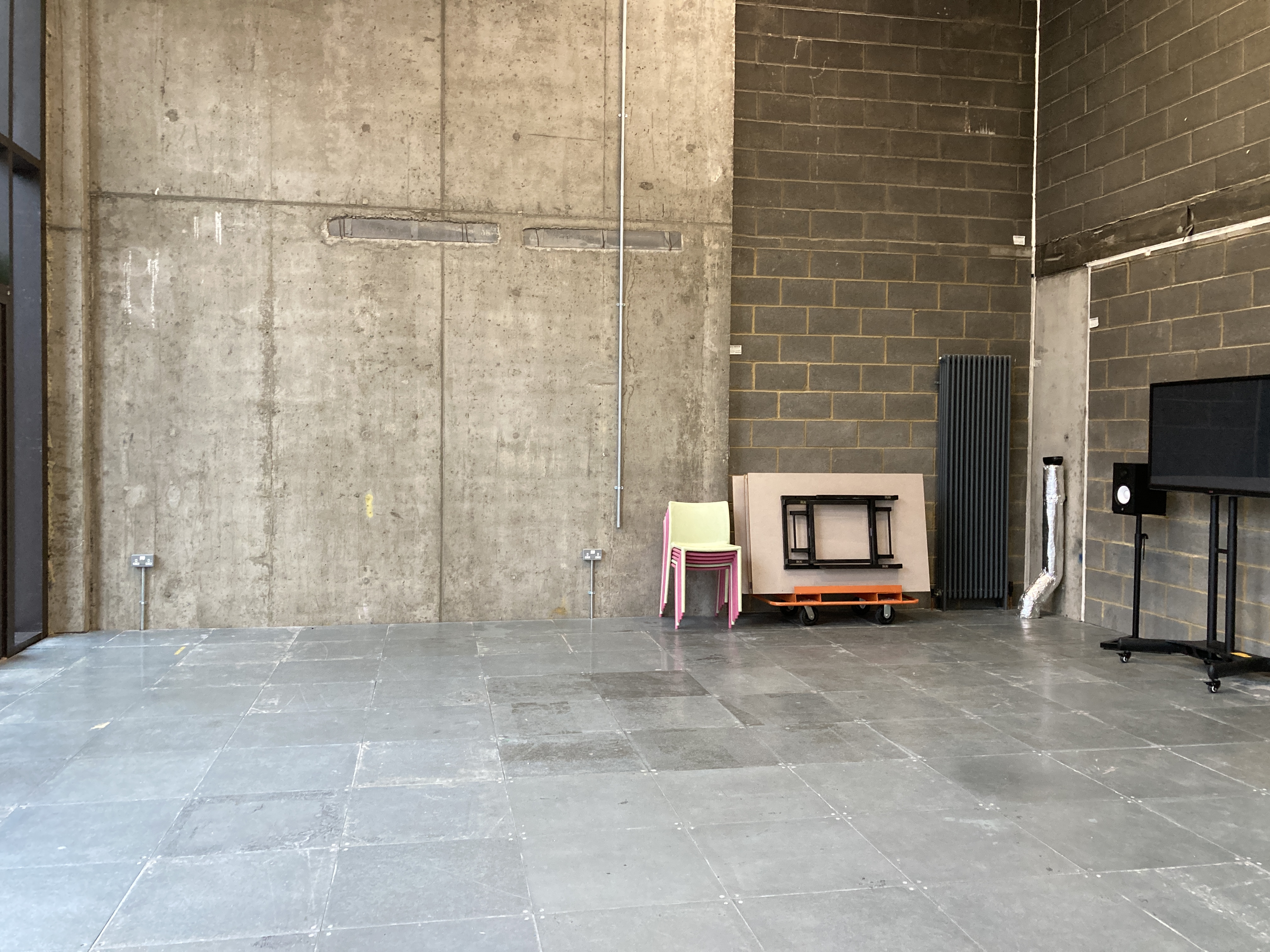 Versatile minimalist event space with concrete walls for corporate meetings and workshops.