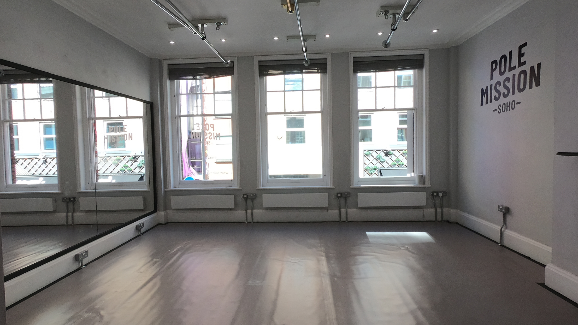 Versatile fitness event space with large windows and mirrored wall for wellness workshops.