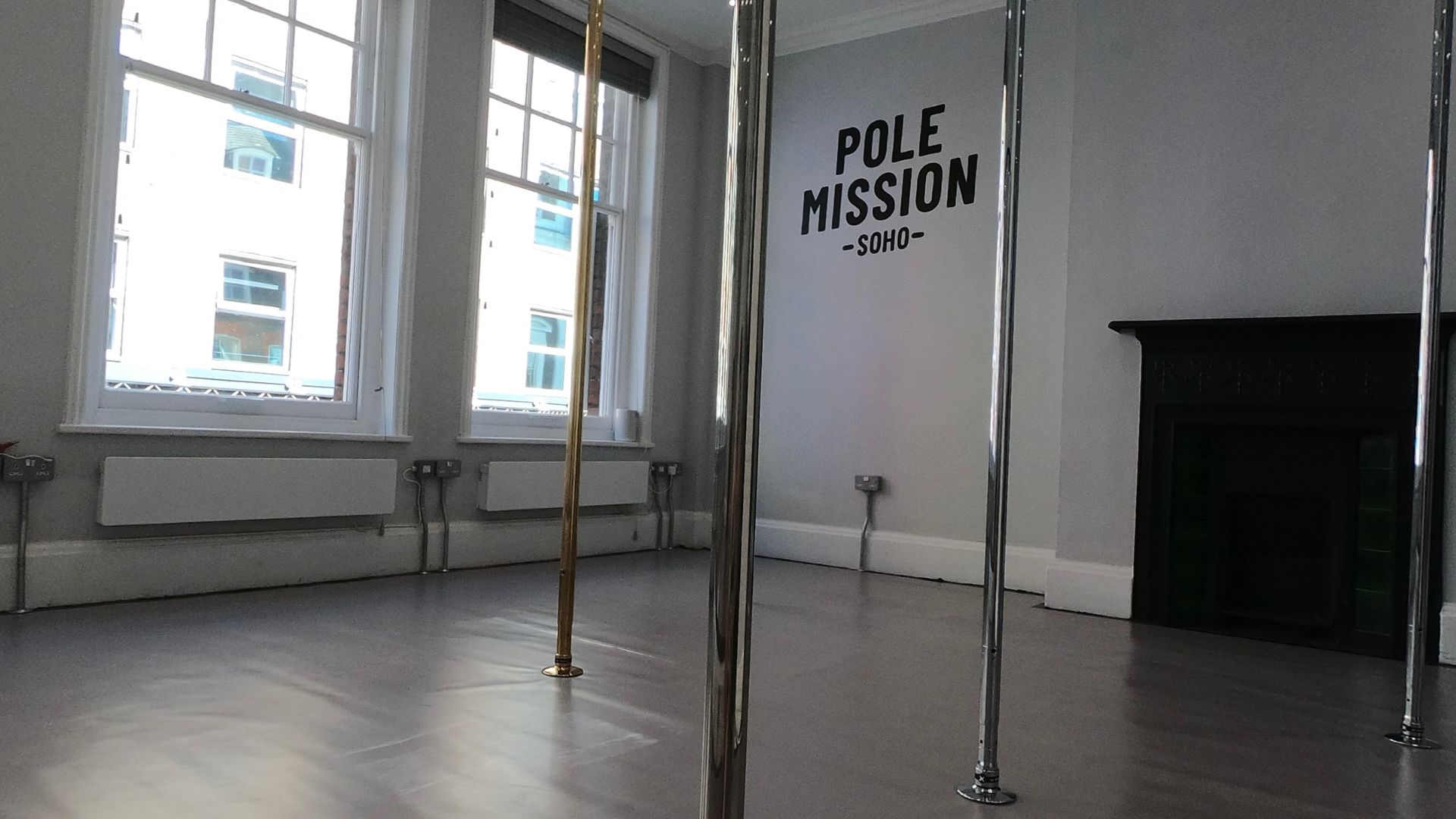 Sleek pole dancing studio with polished floor, ideal for fitness workshops and events.