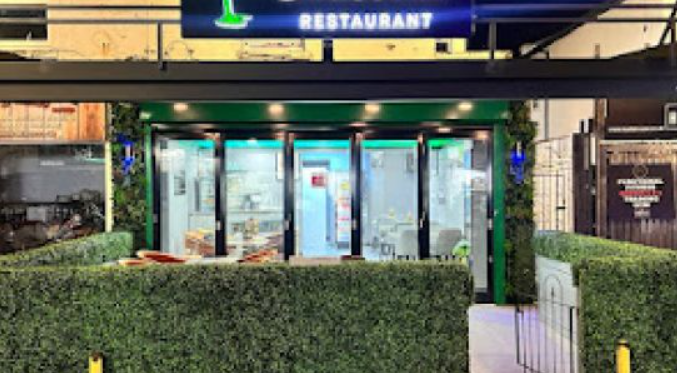 Modern Nande Caribbean Restaurant entrance with greenery, perfect for events and gatherings.