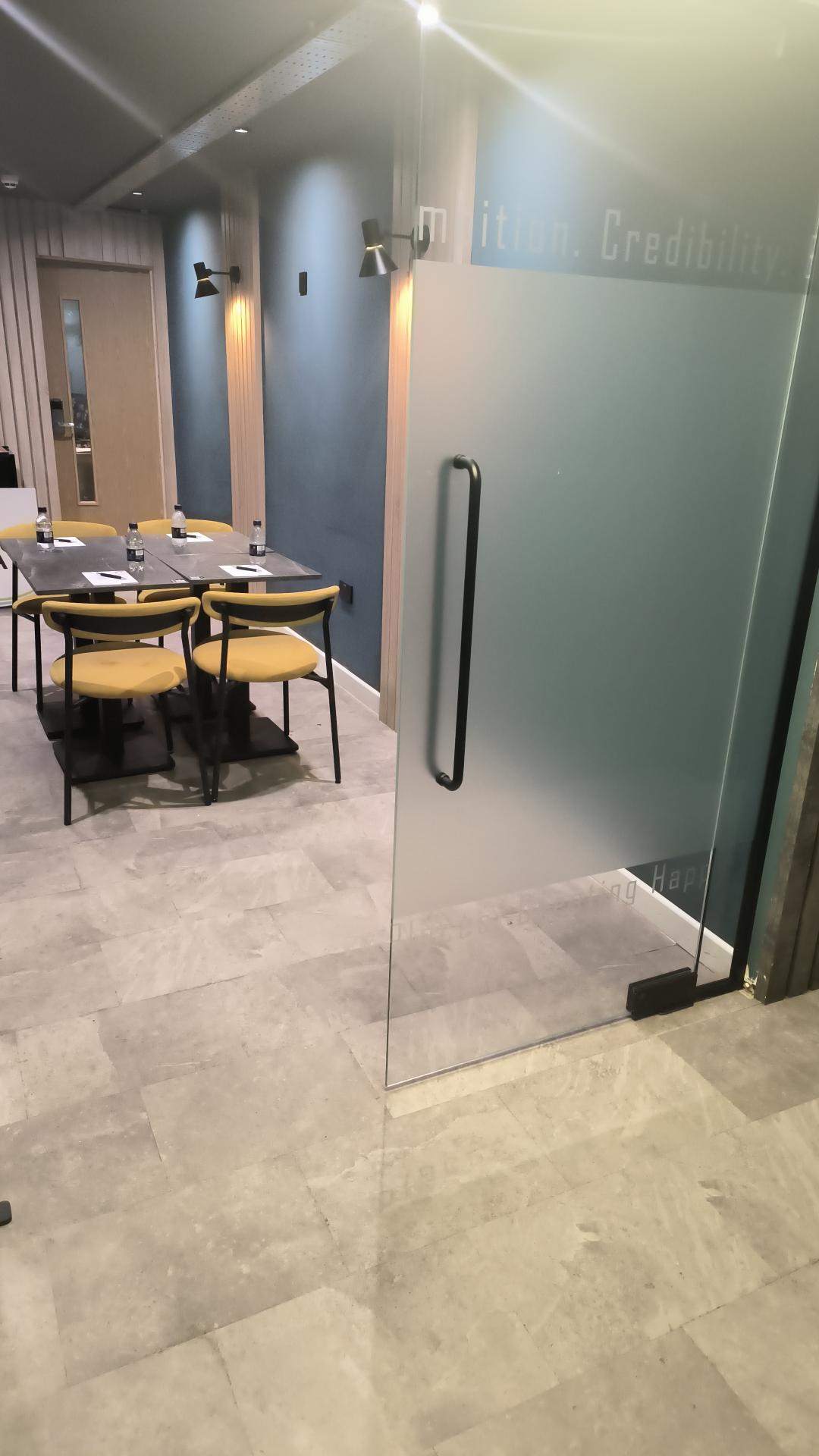 Modern meeting room with glass door and yellow chairs at The Plaza Hotel, Chorley.