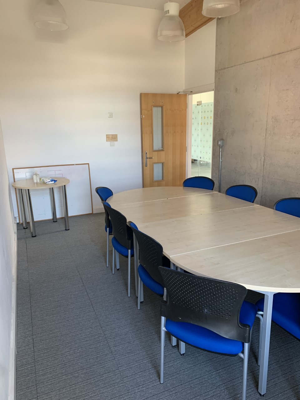 "Modern meeting space with oval table and blue chairs at Knowle West Media Centre."
