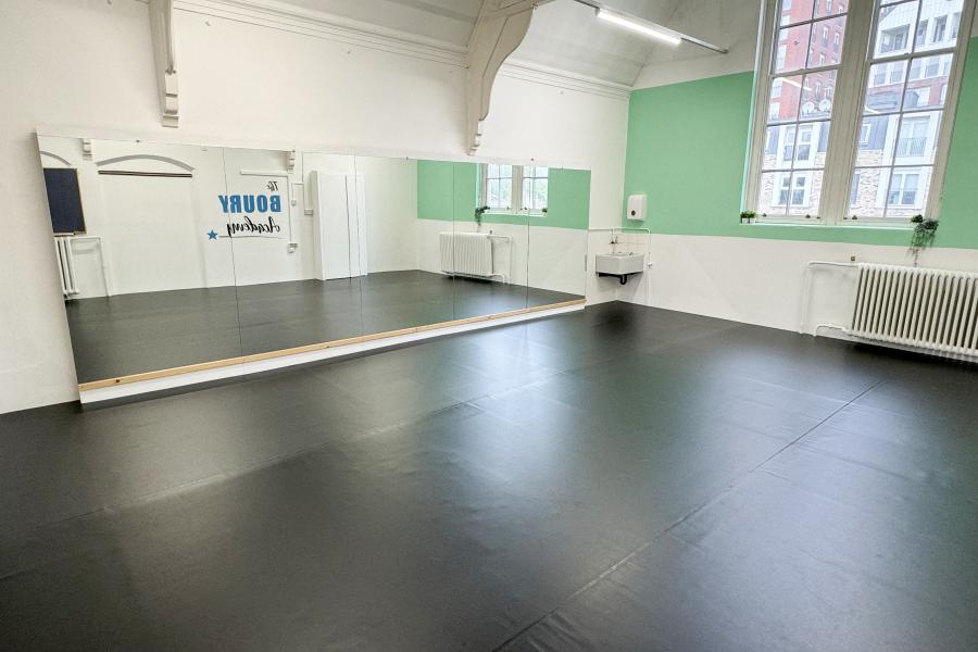 Versatile event space with large mirror, ideal for workshops and fitness classes.