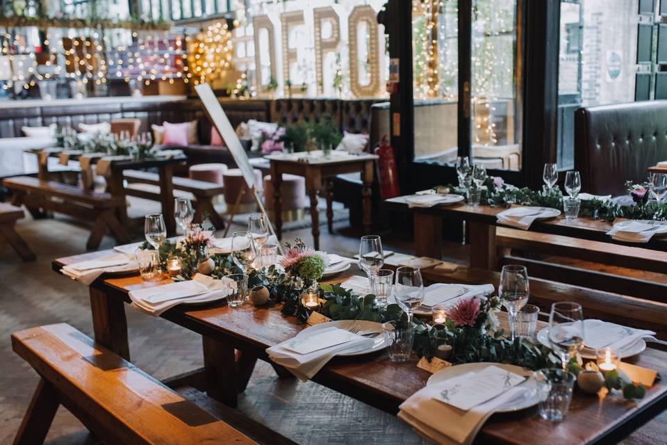 Elegant event space at The Depot N7 with long wooden tables and floral centerpieces.