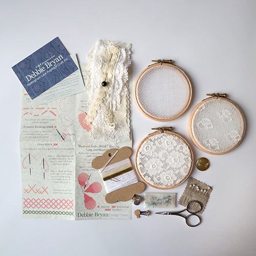 Craft kits for textile arts workshop with embroidery hoops and lace samples.