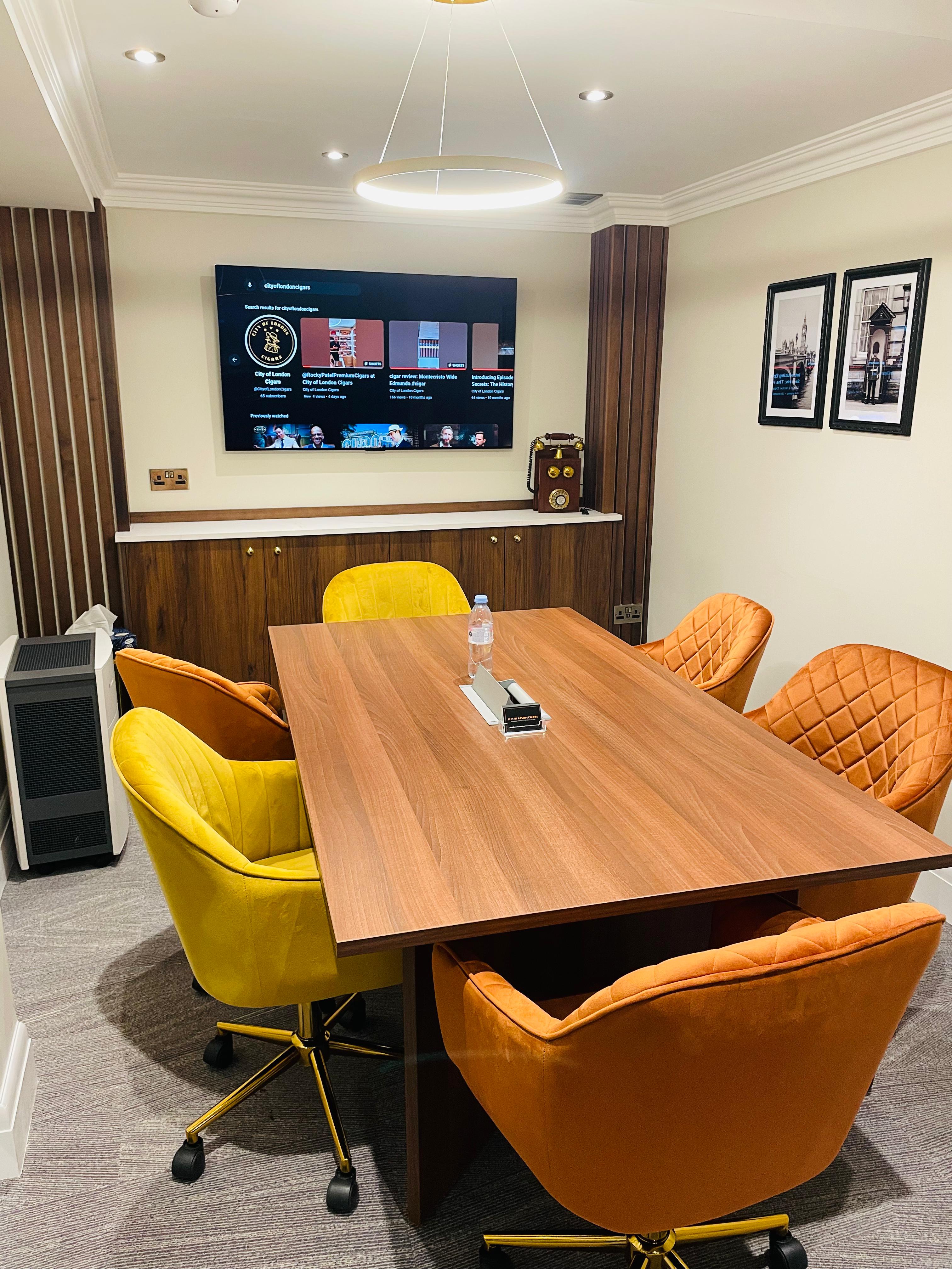 Modern meeting room with wooden table, colorful chairs for collaboration events.