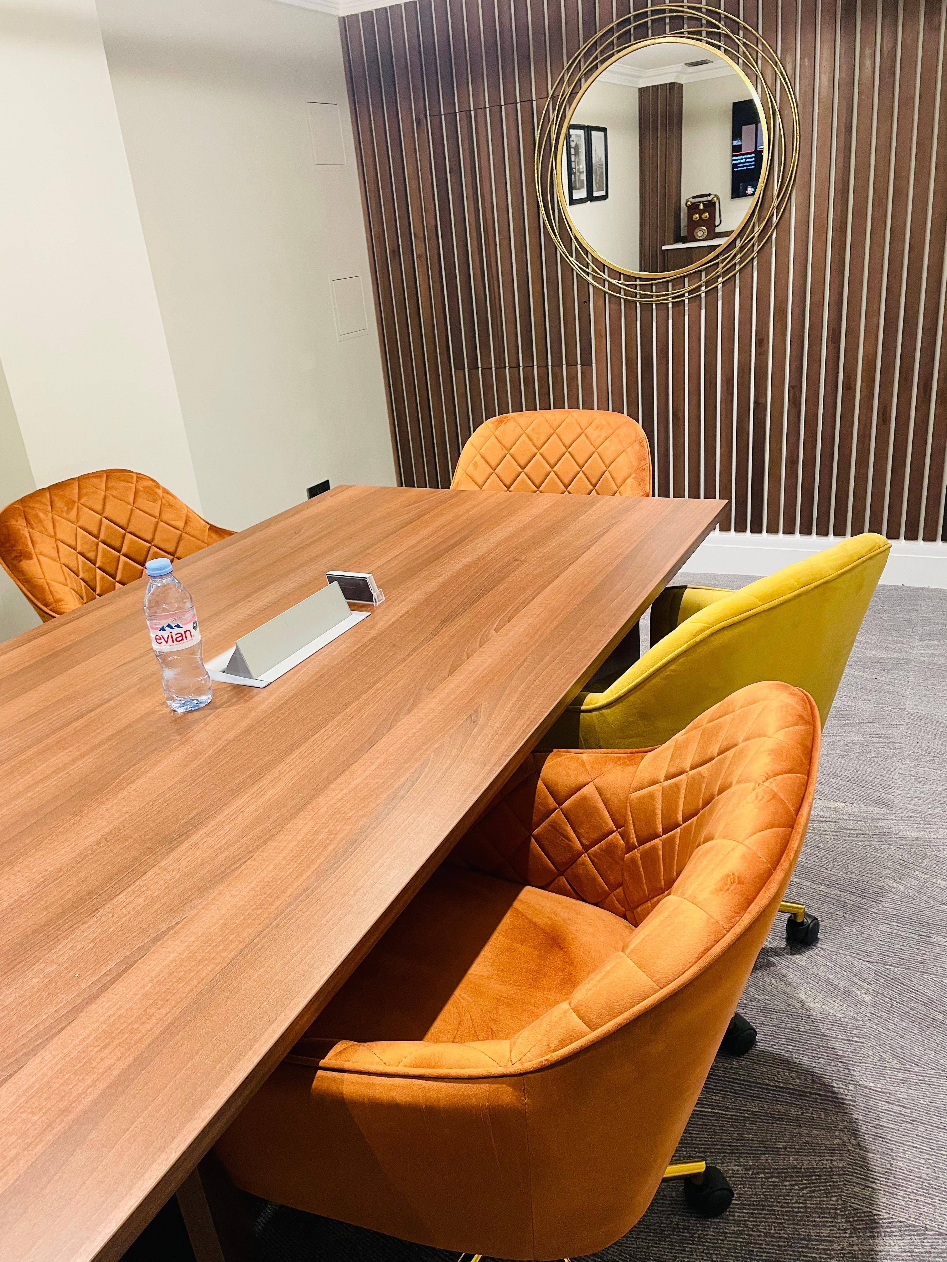 Modern meeting space with a wooden table and colorful chairs for collaborative events.