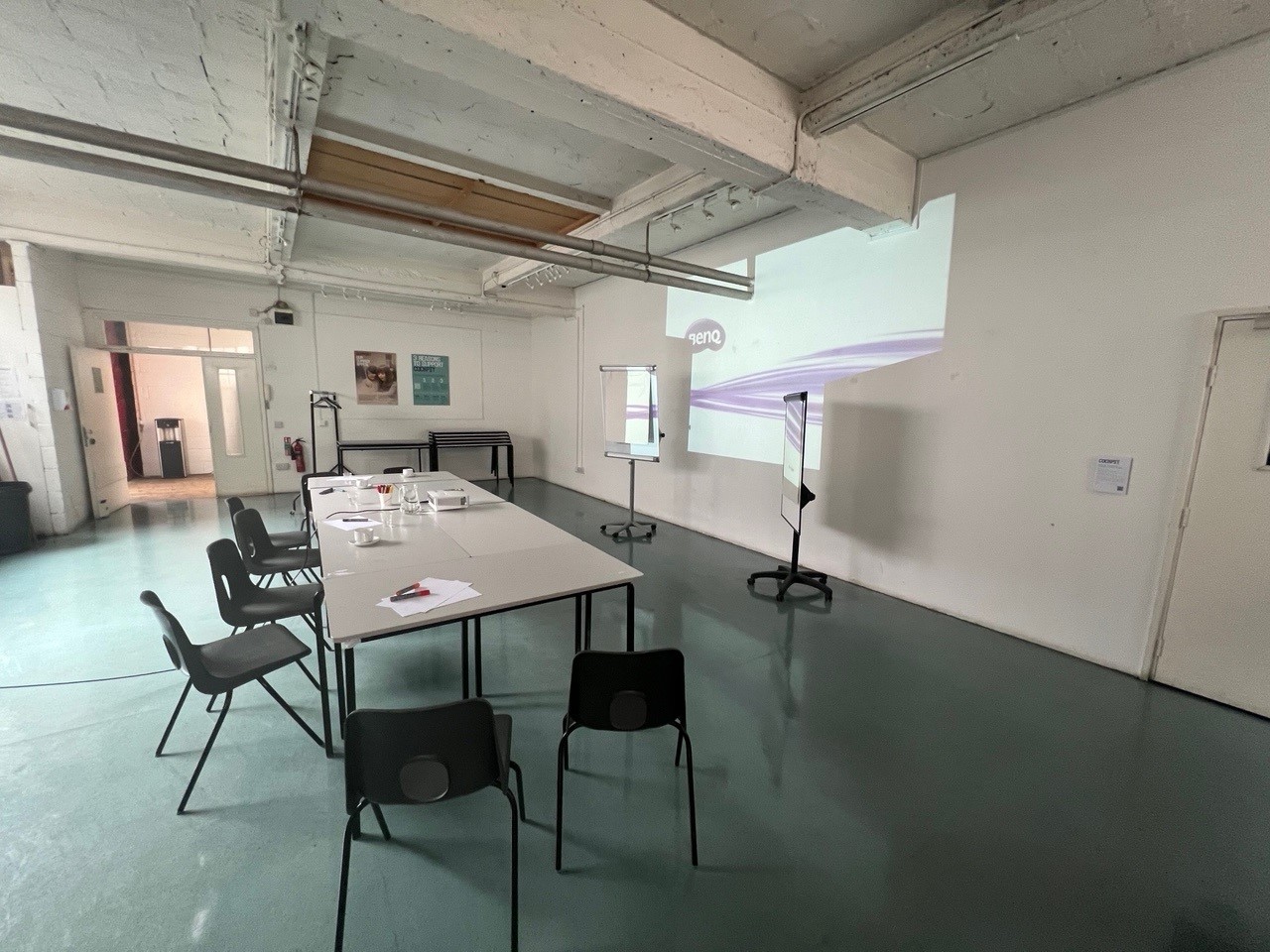 Versatile meeting space with long table, ideal for workshops and presentations.