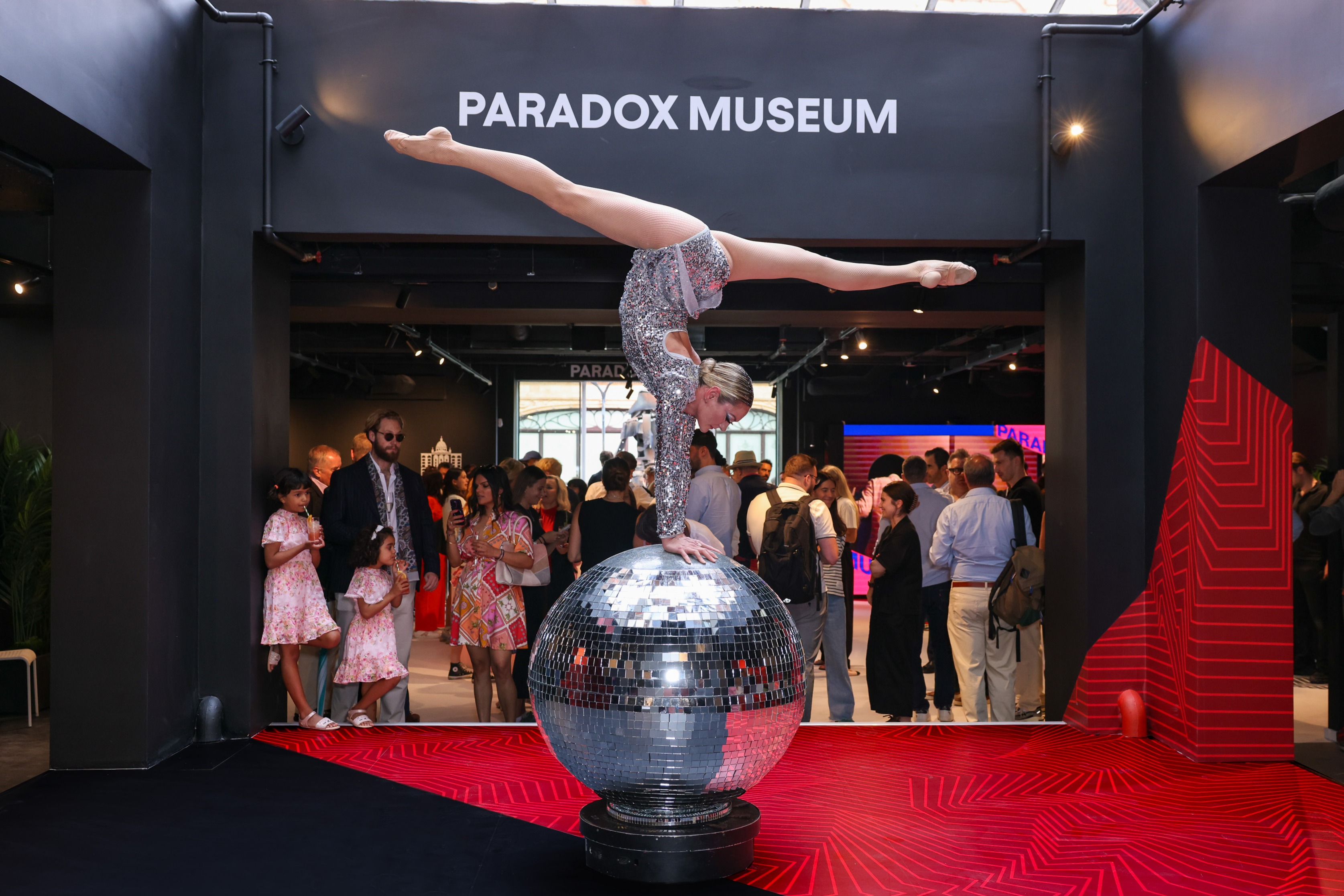 Acrobat on disco ball at Paradox Museum London event space, art and entertainment.