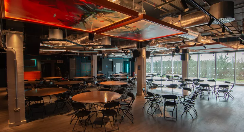 Versatile lobby event space with round tables and vibrant decor at The Forum Hertfordshire.