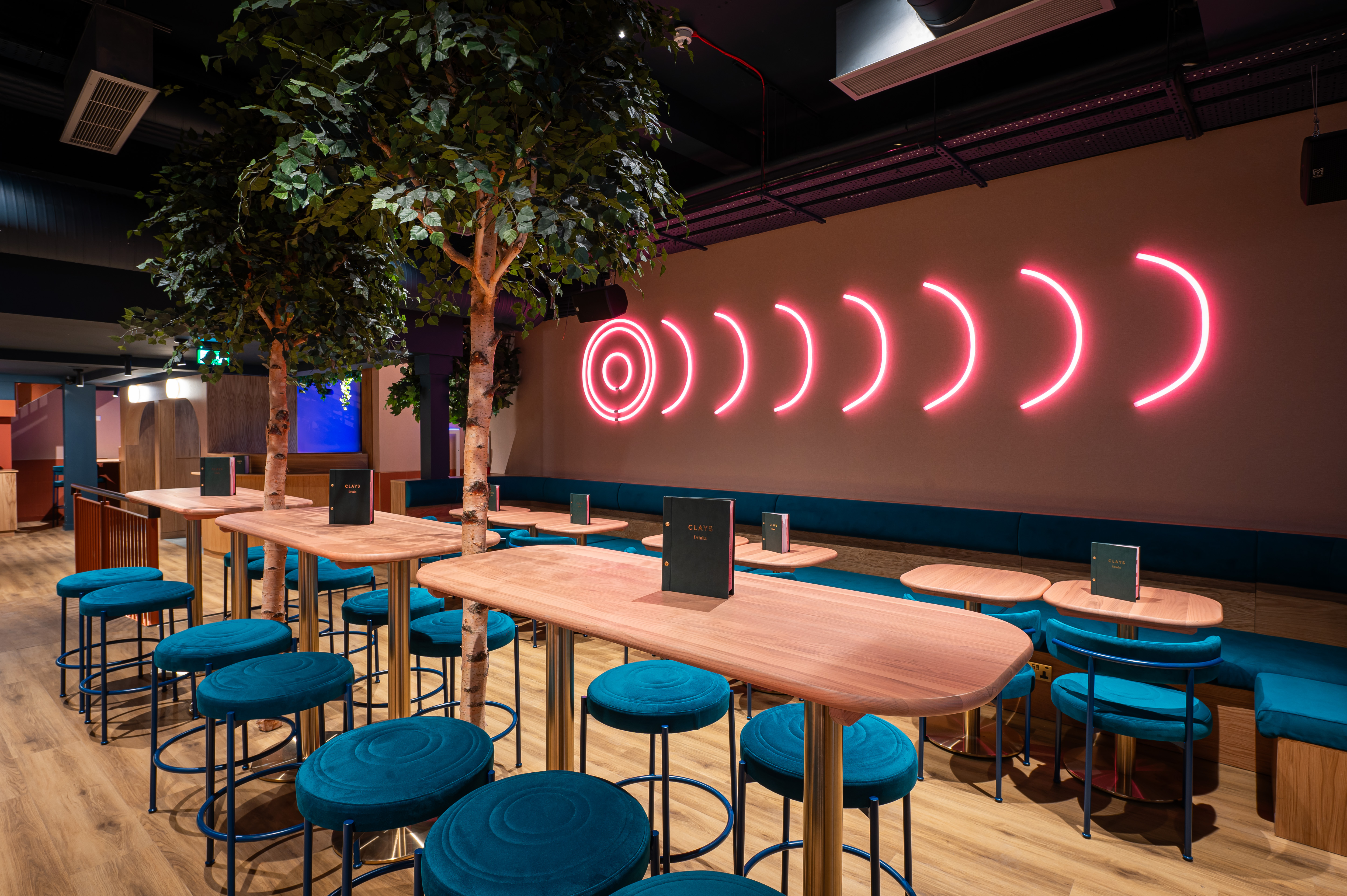 Modern event space in Clays Birmingham with sleek tables and vibrant blue stools.