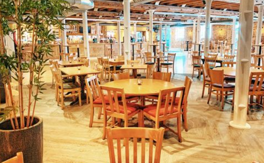 Spacious Warehouse Bar dining area with wooden tables, ideal for casual meetings and events.
