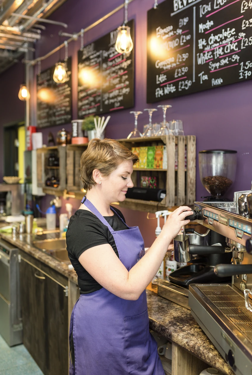 Barista preparing coffee in vibrant YMCA/Purplespoon Cafe for events and meetings.