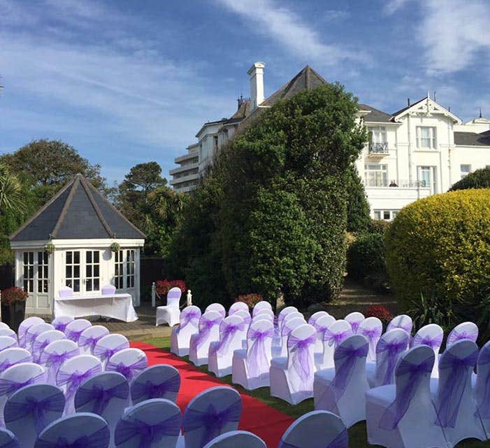 Secret Garden at Royal Bath Hotel: elegant outdoor wedding venue with white chairs and gazebo.