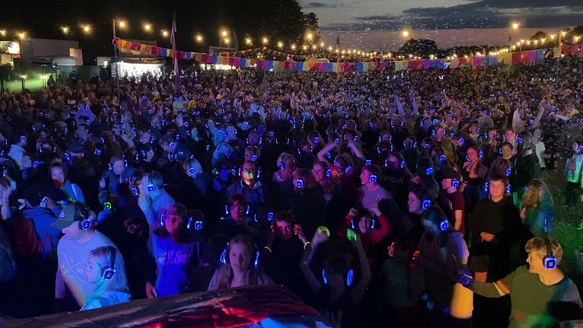 Silent disco festival with vibrant crowd wearing wireless headphones and colorful lighting.