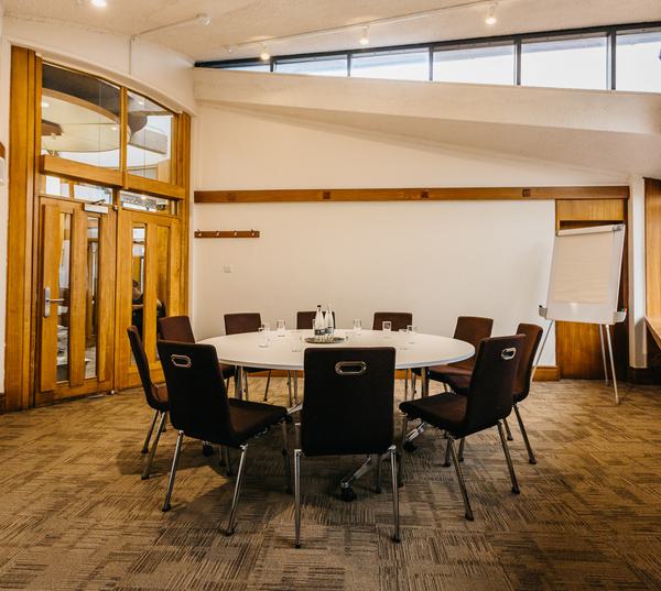 Meeting room with round table and chairs, perfect for collaborative discussions and events.