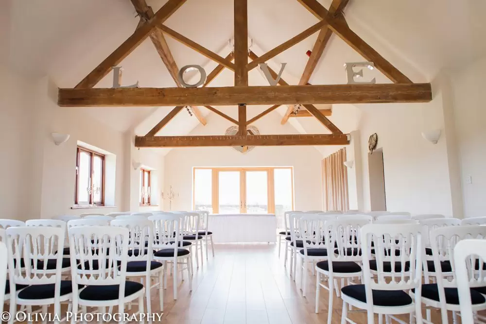Bishops Barn wedding venue with elegant chairs and romantic "LOVE" display.