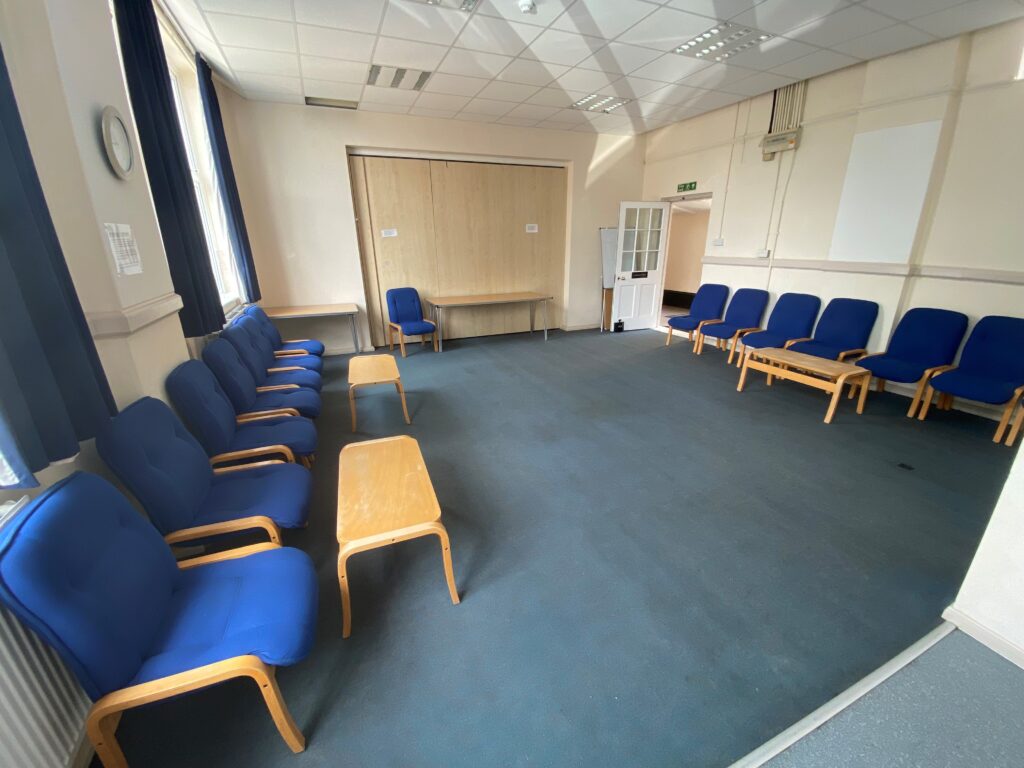 Spacious meeting room with blue chairs for workshops at The Oaks Community Hall.