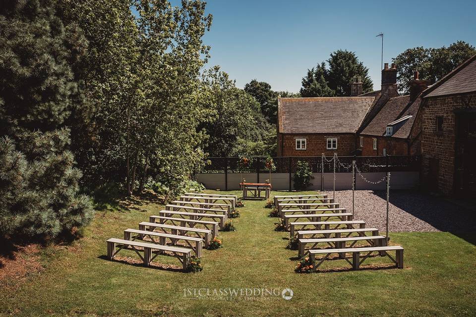 Catesby Barn wedding venue with wooden benches and lush greenery for intimate ceremonies.