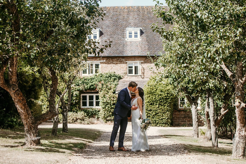 Catesby Barn at Dodmoor House: rustic wedding venue with lush greenery backdrop.