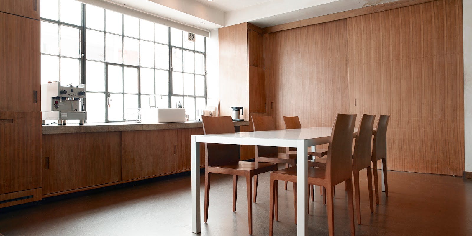 Modern meeting space with white table and wooden chairs at Robert's Place Studios.