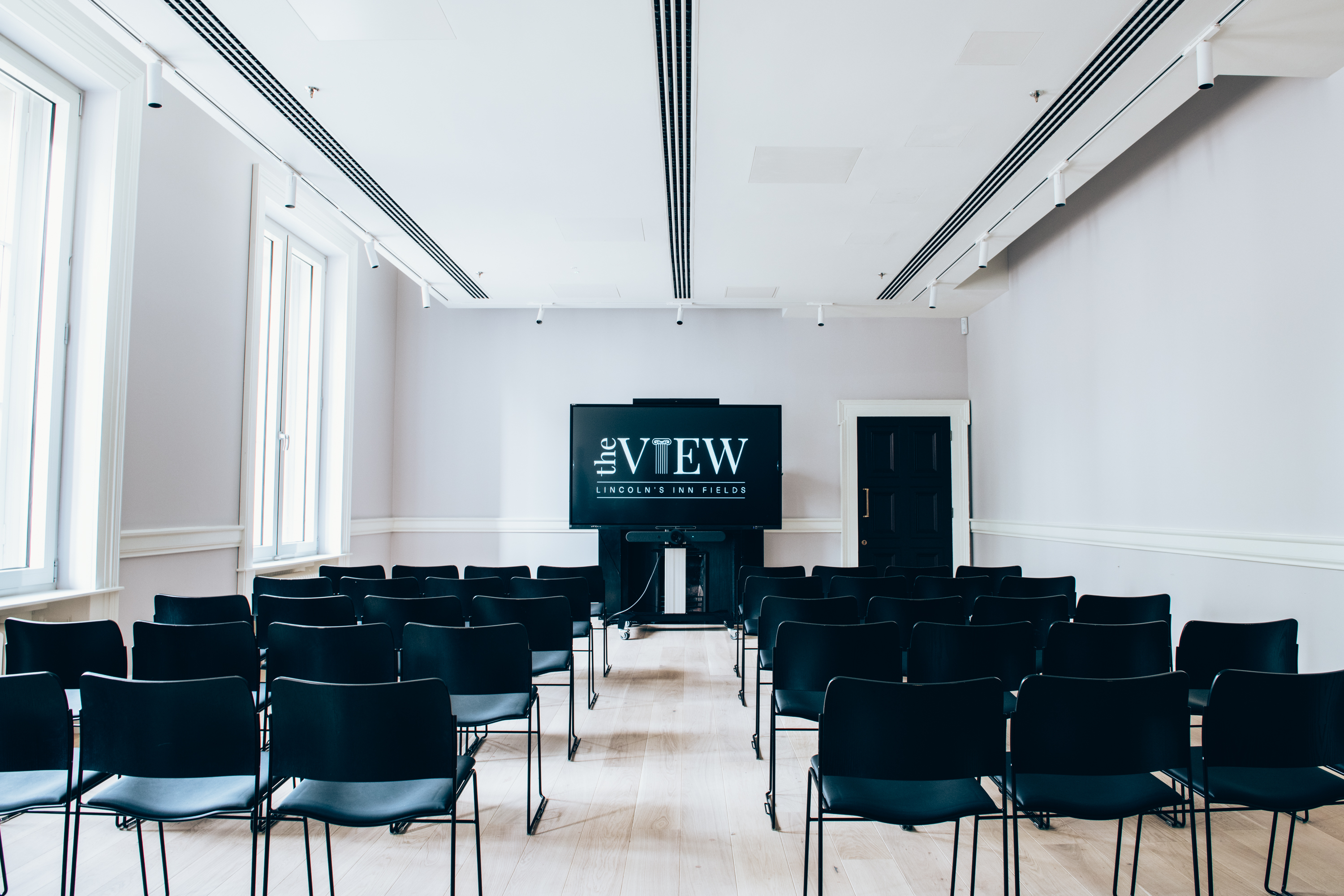 Modern meeting space with black chairs and large screen for corporate events and workshops.