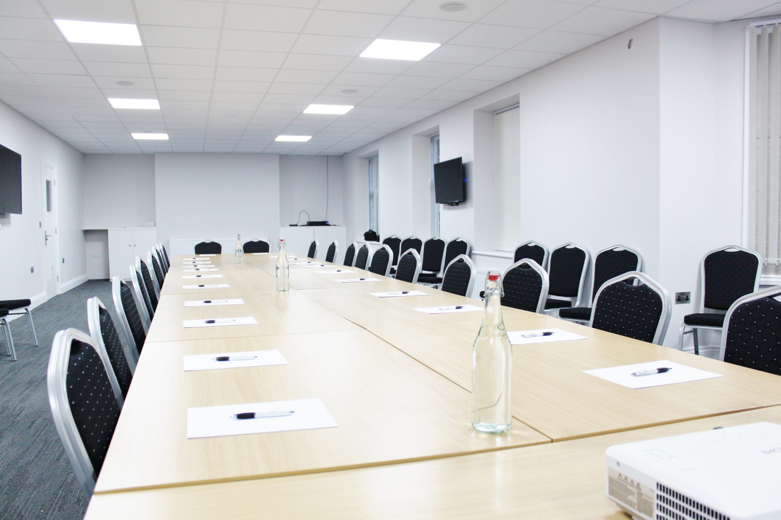 Professional meeting room with long table, notepads, and screens for conferences.