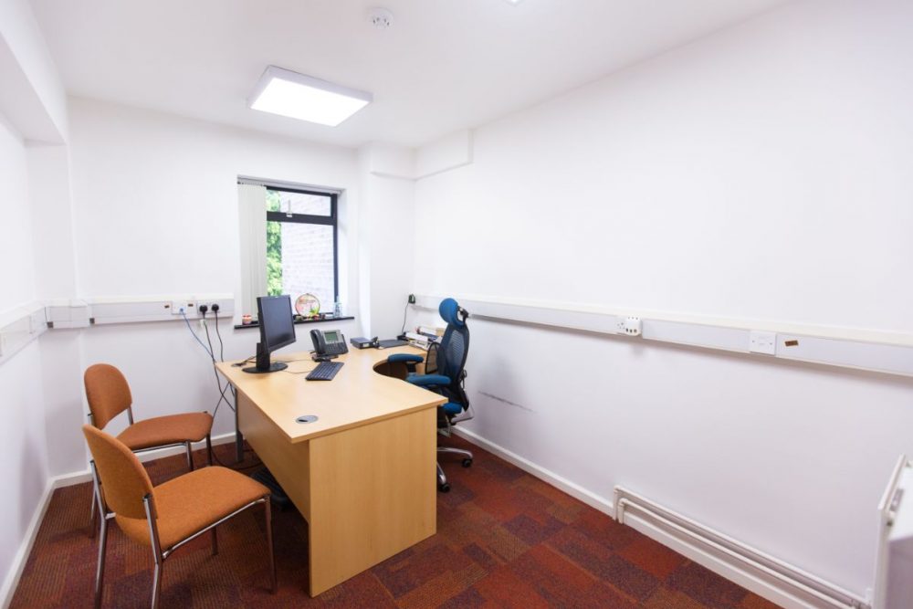 Minimalist meeting space with desk and chairs for focused discussions in AMI Spaces.