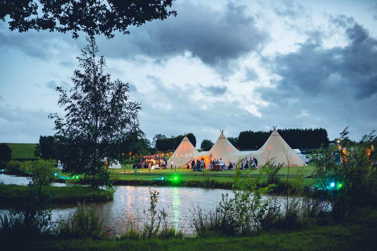 Outdoor wedding venue with tipis by a serene pond, perfect for events and retreats.
