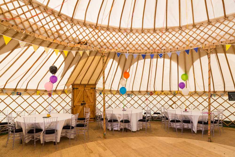Yurt wedding venue with elegant tables, balloons, and warm lighting for events.