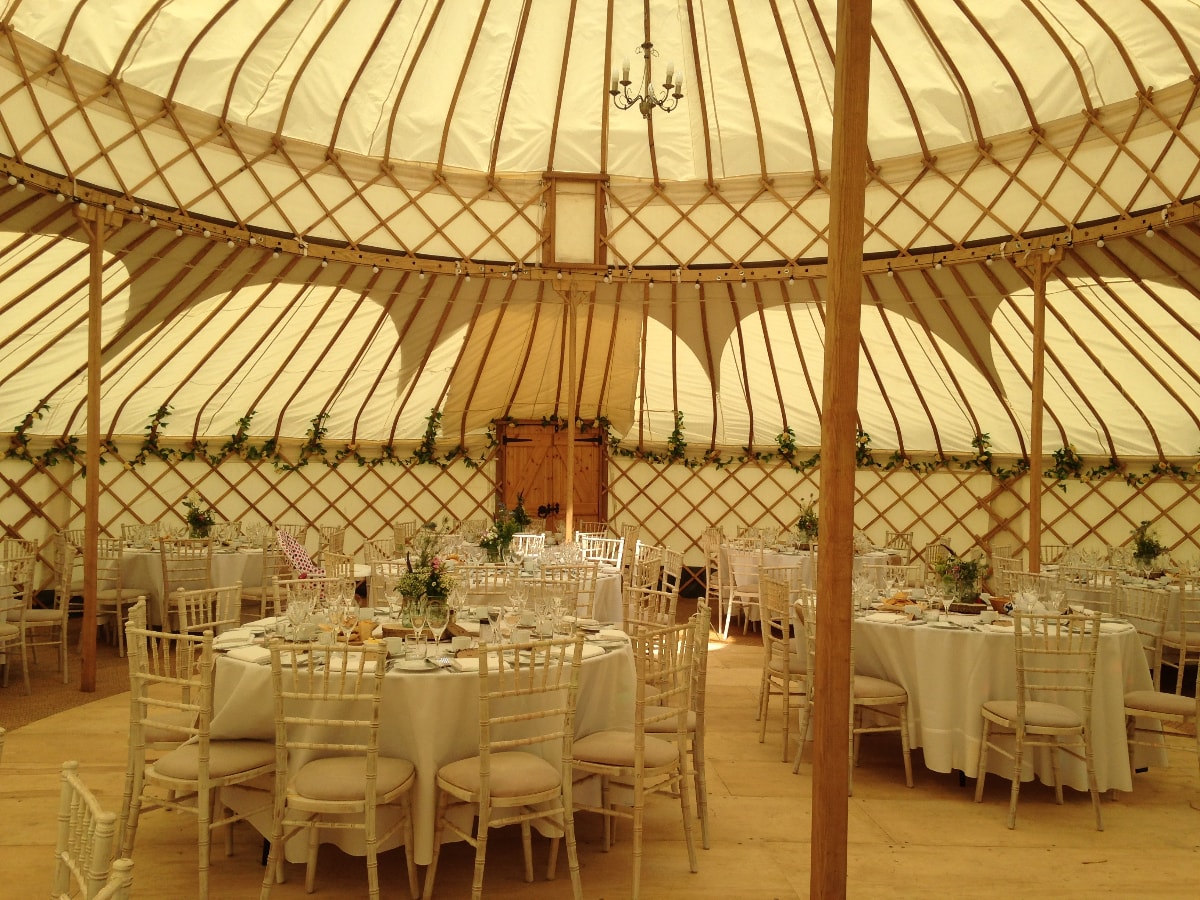 Elegant yurt venue with round tables for unique weddings and corporate retreats.