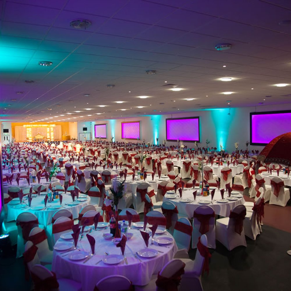 Elegant banquet hall with white tables and red chairs, perfect for weddings and corporate events.