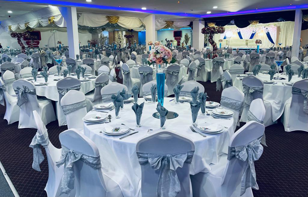Elegant banquet hall with white linens and blue accents for weddings and corporate events.