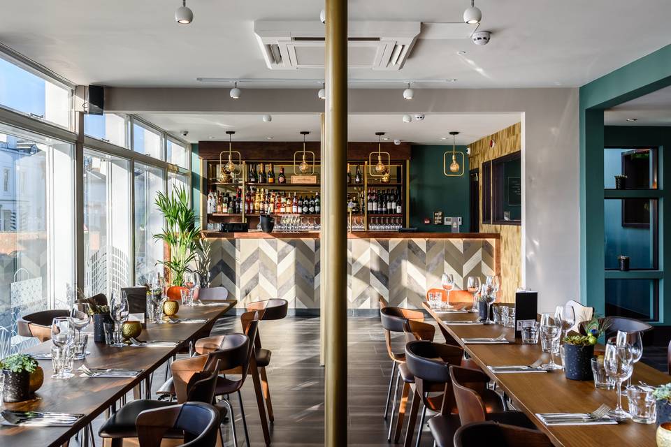 Modern event space with stylish bar and elegant dining tables for corporate meetings.