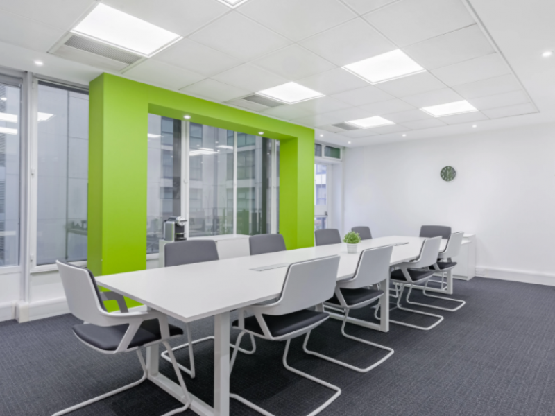 Modern meeting room with white table and green accent wall, perfect for brainstorming sessions.