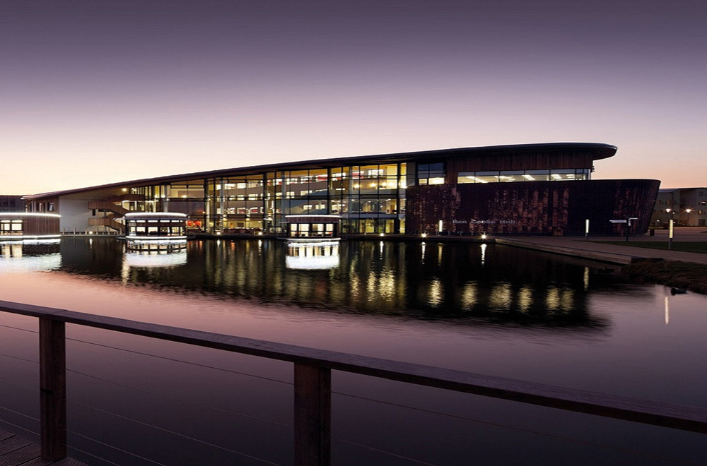 Modern event venue at dusk, sleek architecture by waterfront, ideal for conferences and galas.