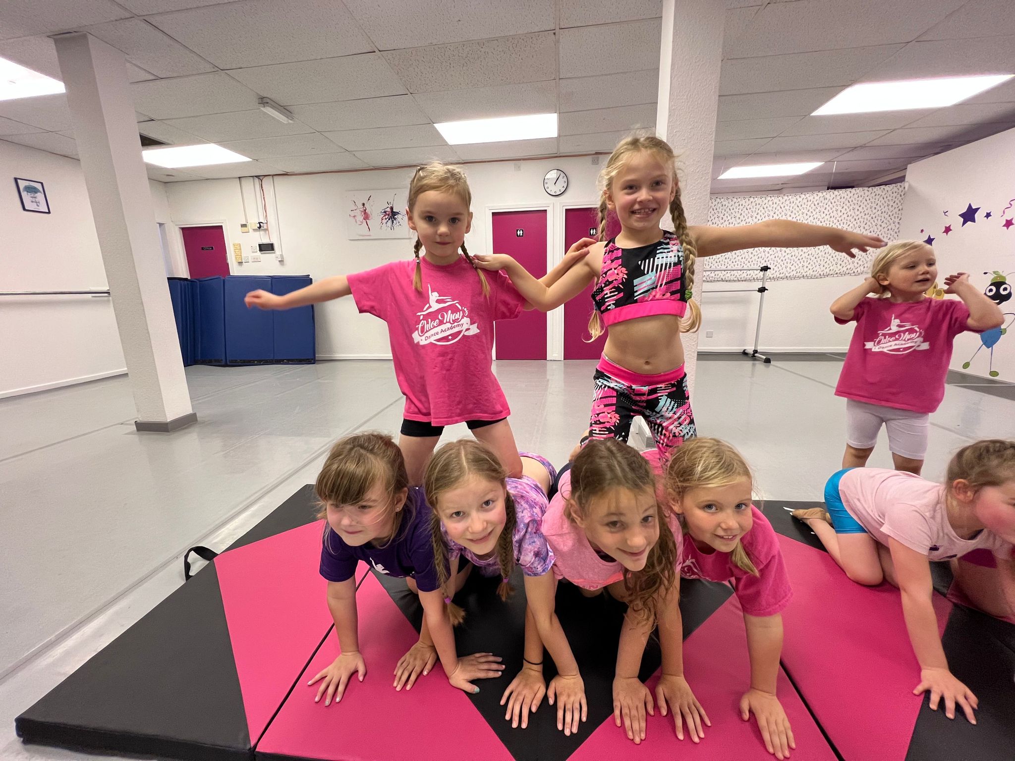 Children in colorful attire engaged in team-building at Chloe May's Dance Academy.