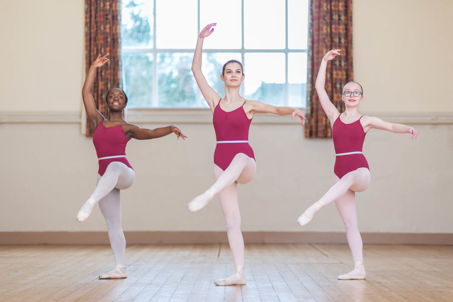 Trio of young ballet dancers in coordinated poses at Rutleigh Norris School of Dance.