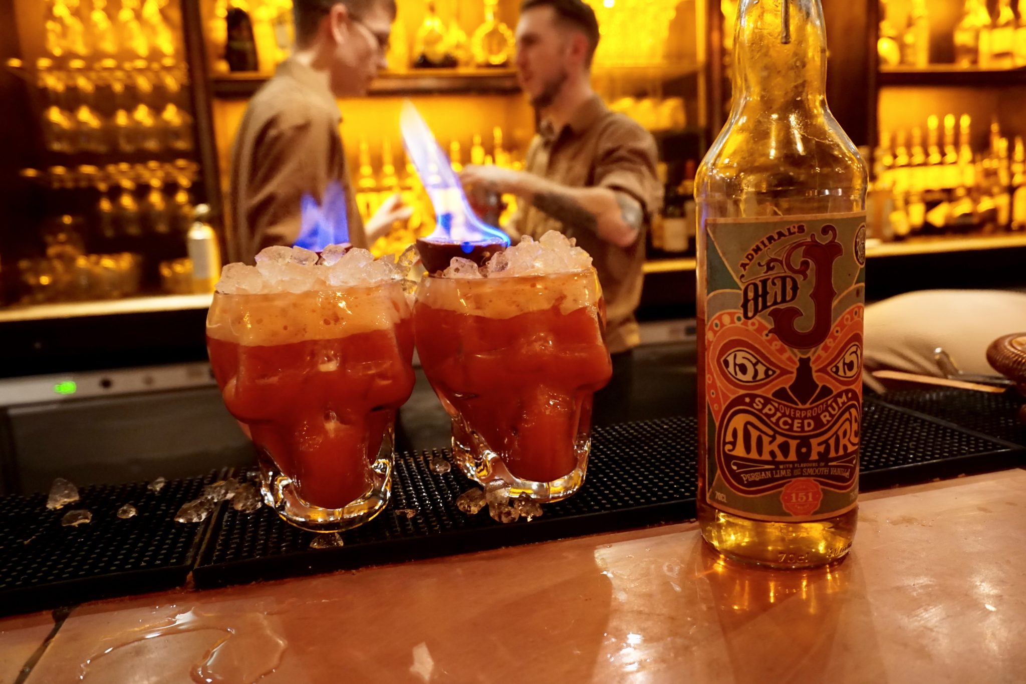 Vibrant cocktail bar in Aluna Birmingham with flaming drinks in skull glasses.