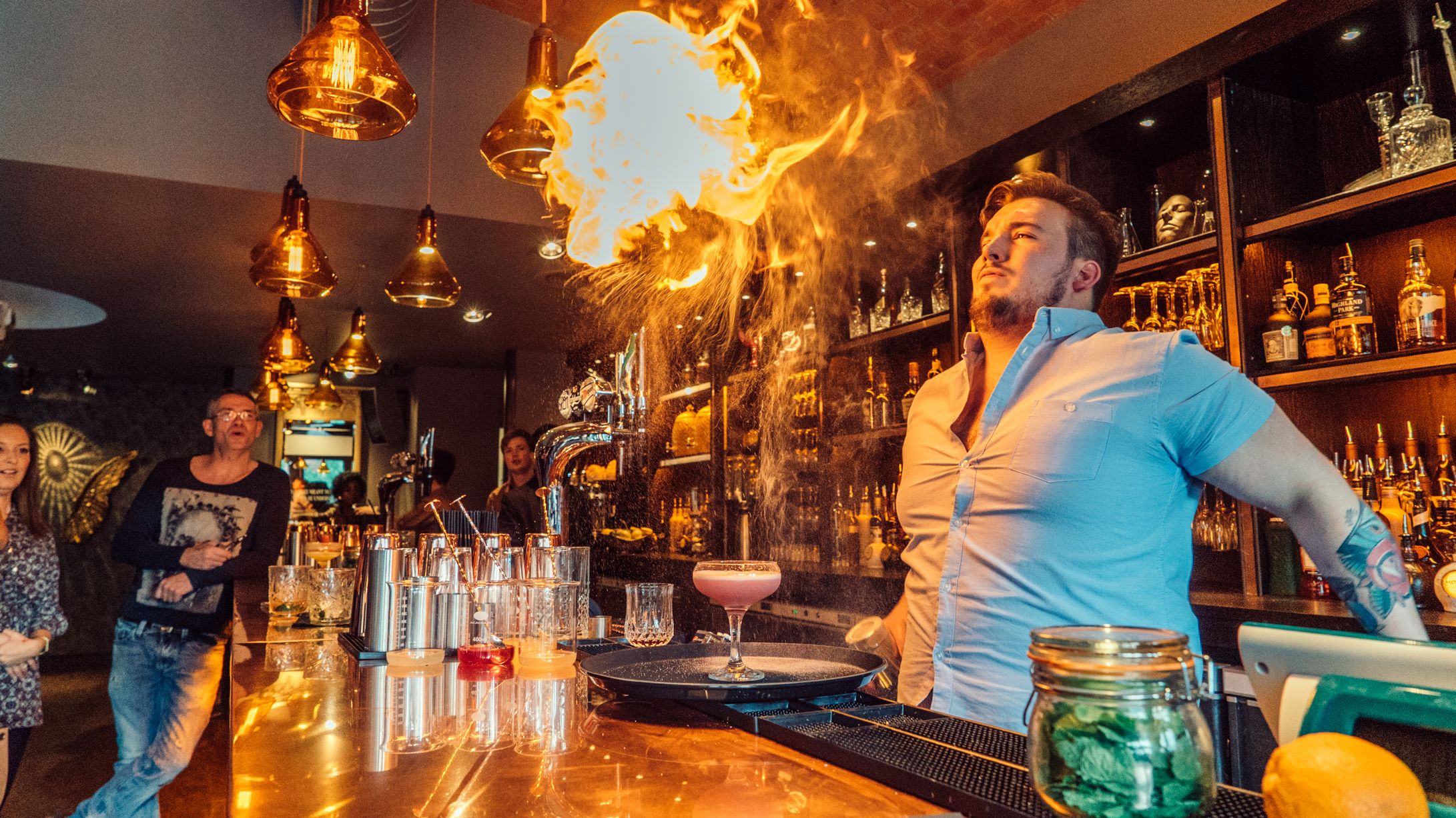 Cocktail bar in Aluna Birmingham with bartender performing flair fire show for events.