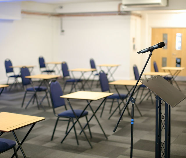 OIKOS Café meeting room setup for presentations with empty tables and chairs.