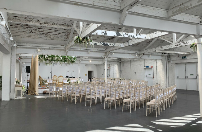 Versatile event space with elegant chairs for weddings and corporate events in bright ambiance.